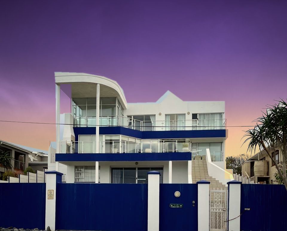 Street view of Beulah at dusk, with its blue gate and white pillars on Hart Street